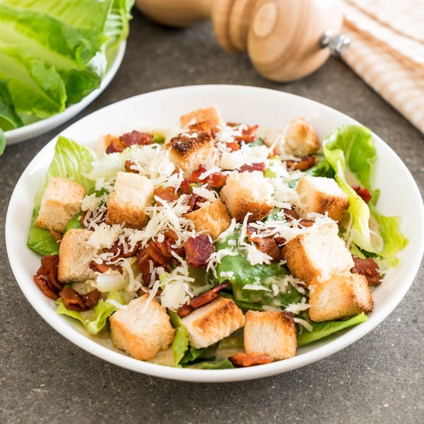 Caesar salad with crisp romaine lettuce, croutons, bacon bits, and shredded Parmesan cheese.
